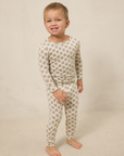 Child wearing a patterned pajama set on a beige background